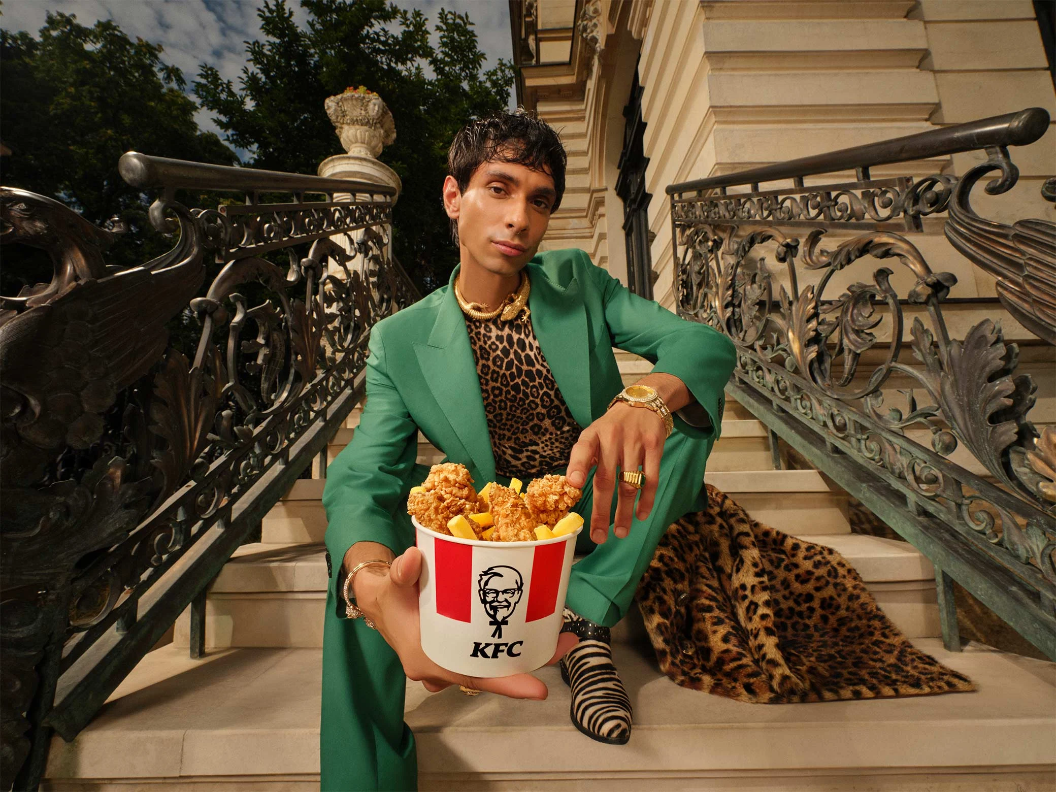 osoba sjedi na stepenicama i drži kfc bucket s hrskavom piletinom i pomfritom