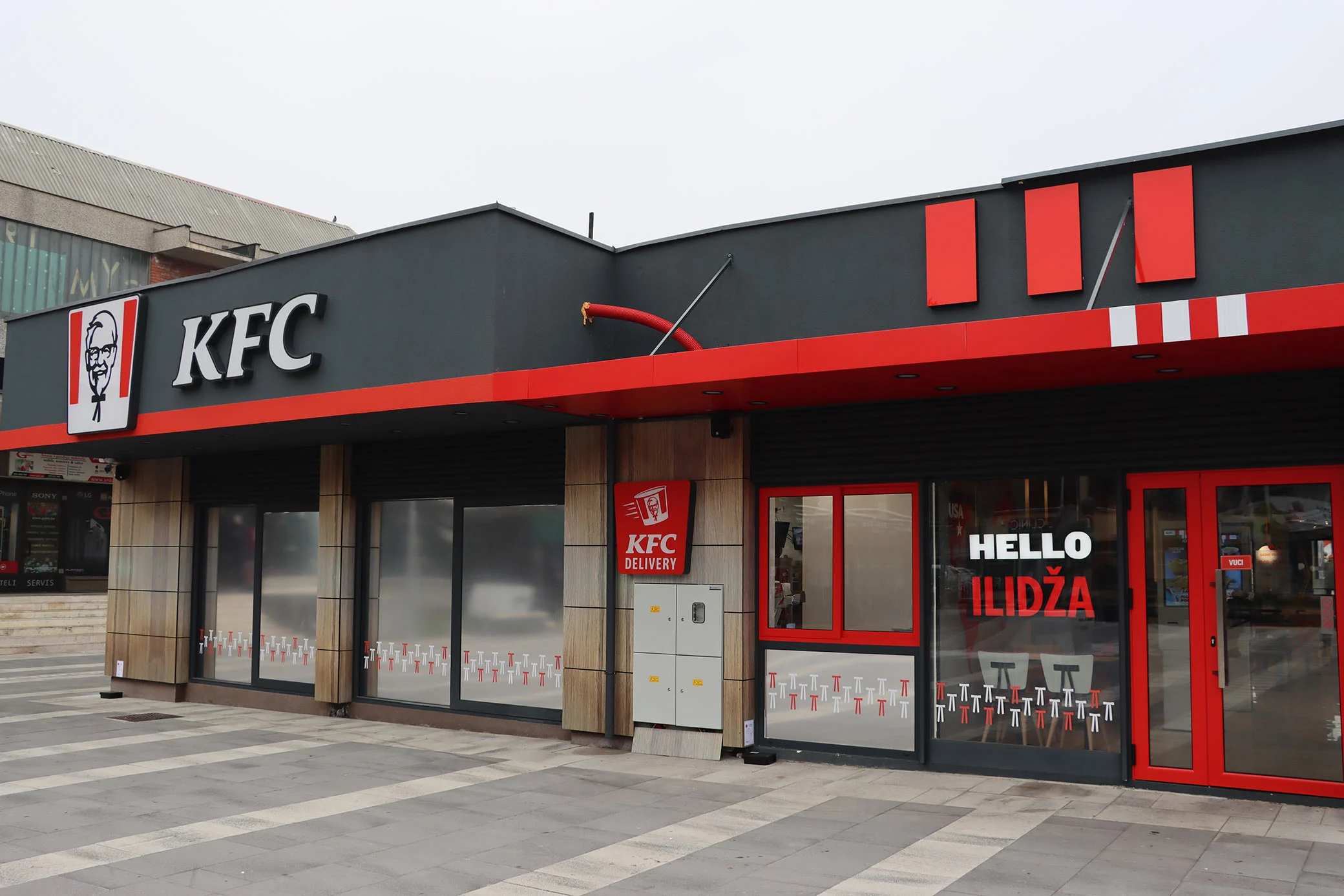 vanjski izgled kfc restorana na ilidži u sarajevu sa prepoznatljivim crveno-crnim brend elementima i ulazom u objekat
